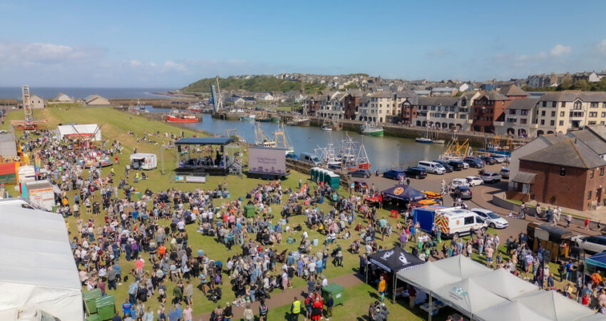 A photo of the taste of the sea festival with lots of people and stands on grass.
